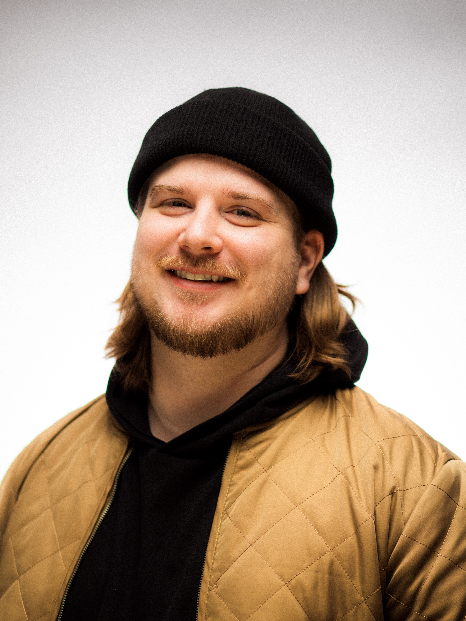 Tom Lincoln, smiling in a black beanie and tan jacket